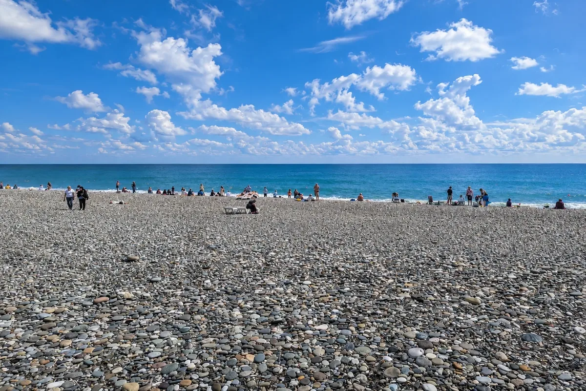 Batumi's pebble beach sloping to the Black Sea under a bright, partly cloudy sky, Adjara, Georgia