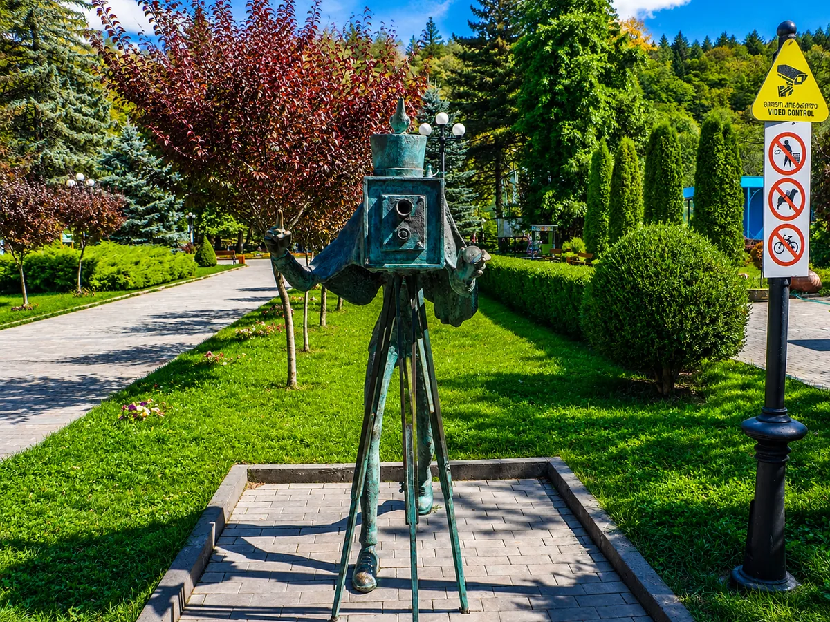 Eine verspielte Bronzestatue eines altmodischen Fotografen mit einer Boxkamera auf Stativbeinen im Zentralpark von Borjomi, Georgien