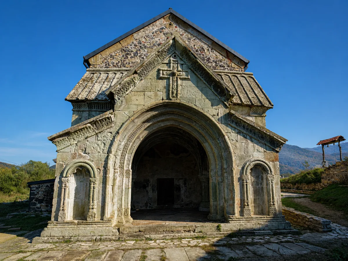 El pórtico de piedra ricamente tallado de la iglesia de Dmanisi Sioni, con un arco apuntado y una cruz ornamentada, Kvemo Kartli, Georgia