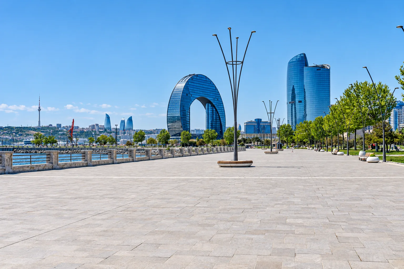 Baku Boulevard, the Caspian seafront promenade, with modern glass towers and an archway building along the waterfront under a blue sky, Azerbaijan