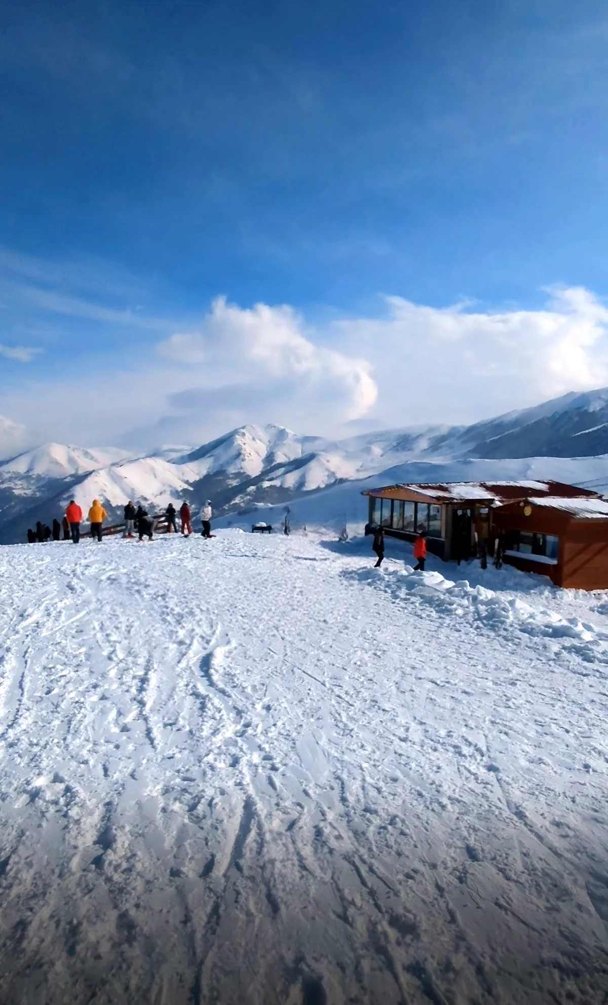 Skiërs en een pistecafé op een besneeuwd plateau met bergzicht in Bakuriani, Georgië