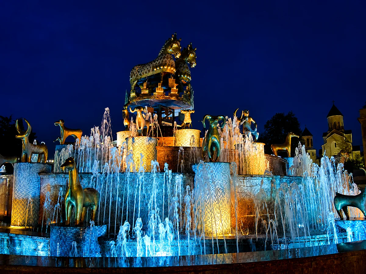 Goldene kolchische Tierfiguren und Wasserstrahlen des Kolchis-Brunnens bei Nacht blau beleuchtet, Kutaissi, Georgien