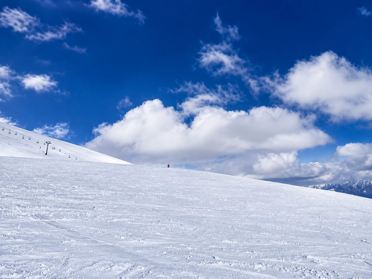 A wide groomed piste and lift line under a blue sky at Gudauri, Georgia