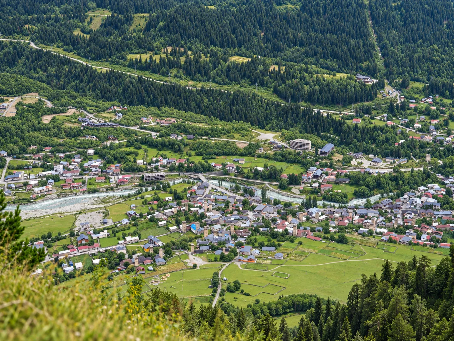 Luftaufnahme von Mestia mit mittelalterlichen swanischen Steintürmen zwischen den Häusern am Fluss Enguri, Oberswanetien, Georgien