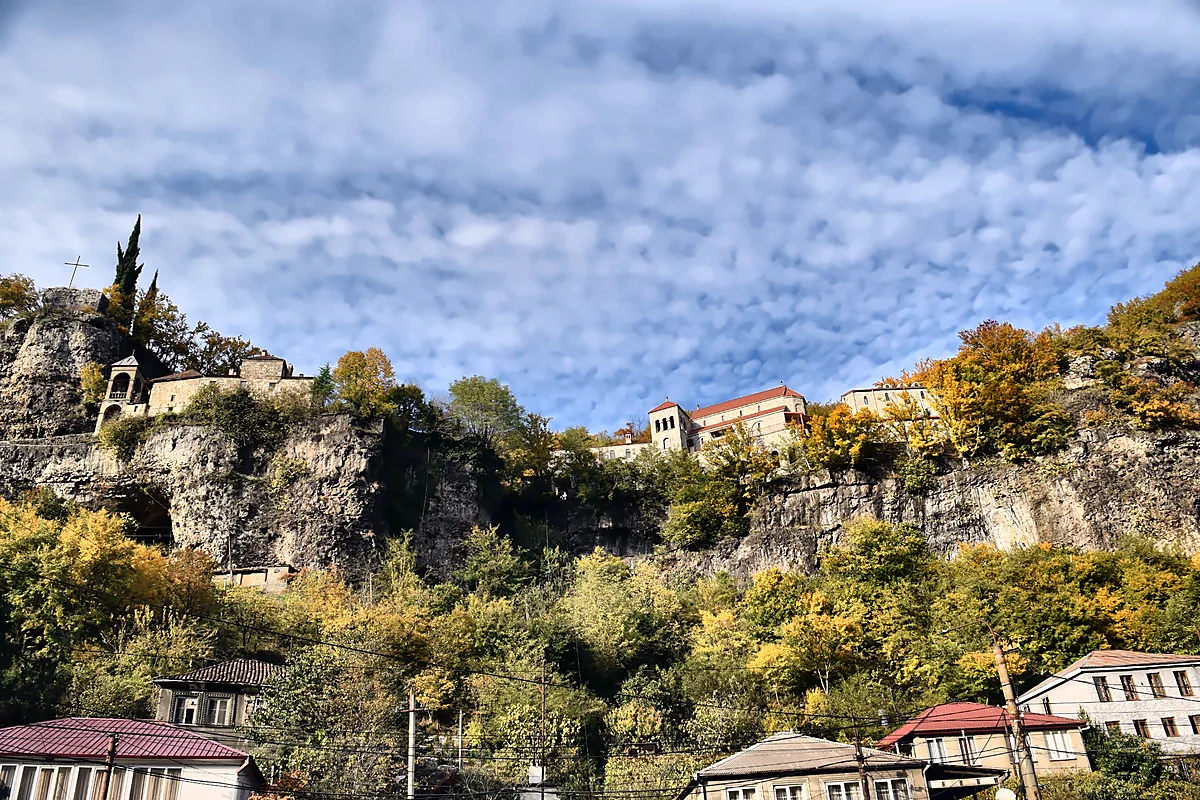 Klasztor Mghvimevi na wapiennym klifie nad domami Cziatury jesienią, Imeretia, Gruzja