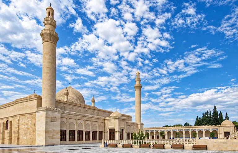 Páteční mešita Džuma v Šamachy, velká mešita ze světlého kamene s vysokými minarety a kupolí pod oblohou posetou mraky, Ázerbájdžán