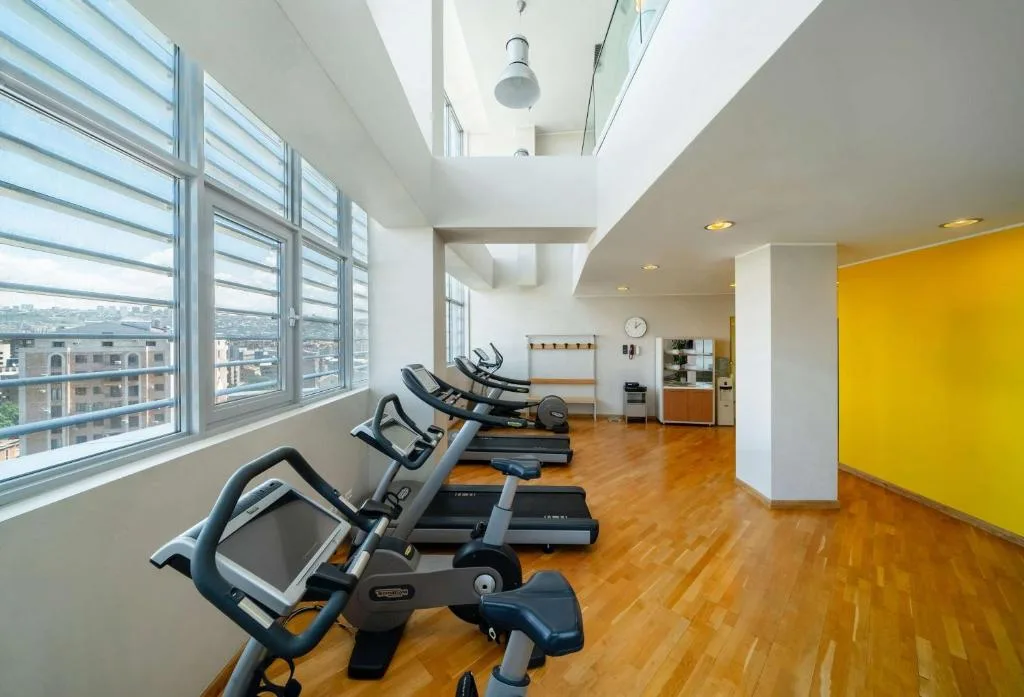 Salle de sport du DoubleTree by Hilton Yerevan City Centre avec équipement cardio et vue sur la ville