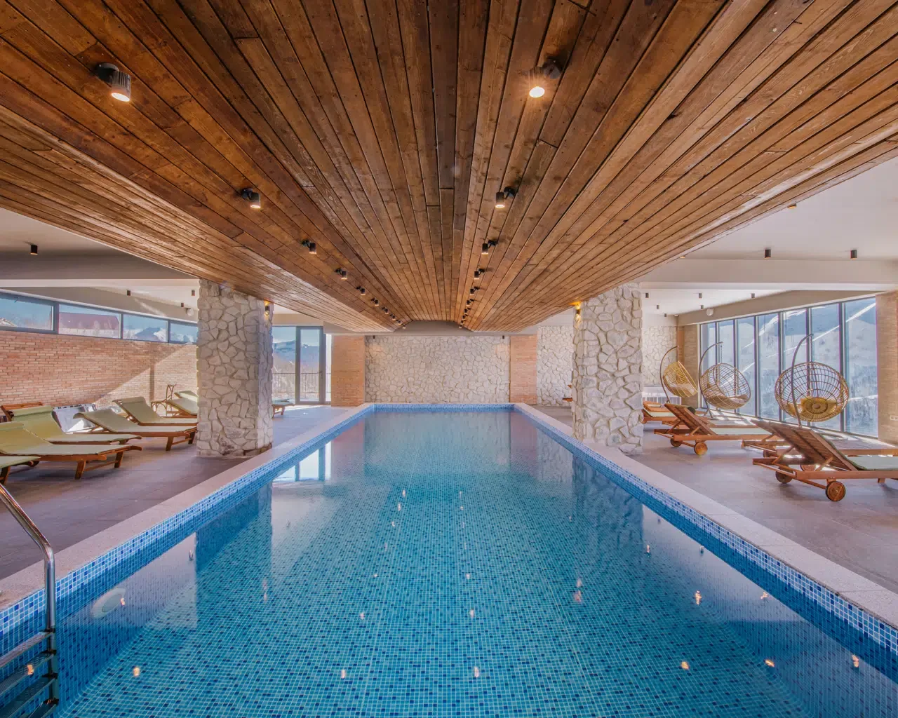 Hallenbad mit Liegen und Fenstern zu den Bergen im Gudauri Inn in Gudauri, Georgien