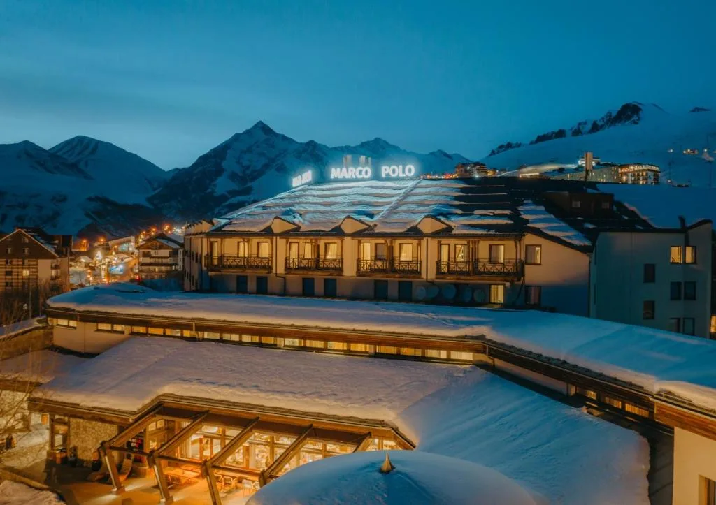 Marco Polo Hotel Gudauri bei Nacht mit beleuchtetem Schriftzug und verschneiten Bergen, Georgien