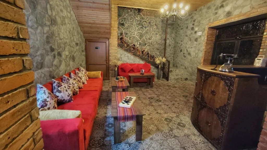 Recepcja z czerwonymi sofami i rzeźbioną ladą, Old Town Sheki w Szeki, Azerbejdżan