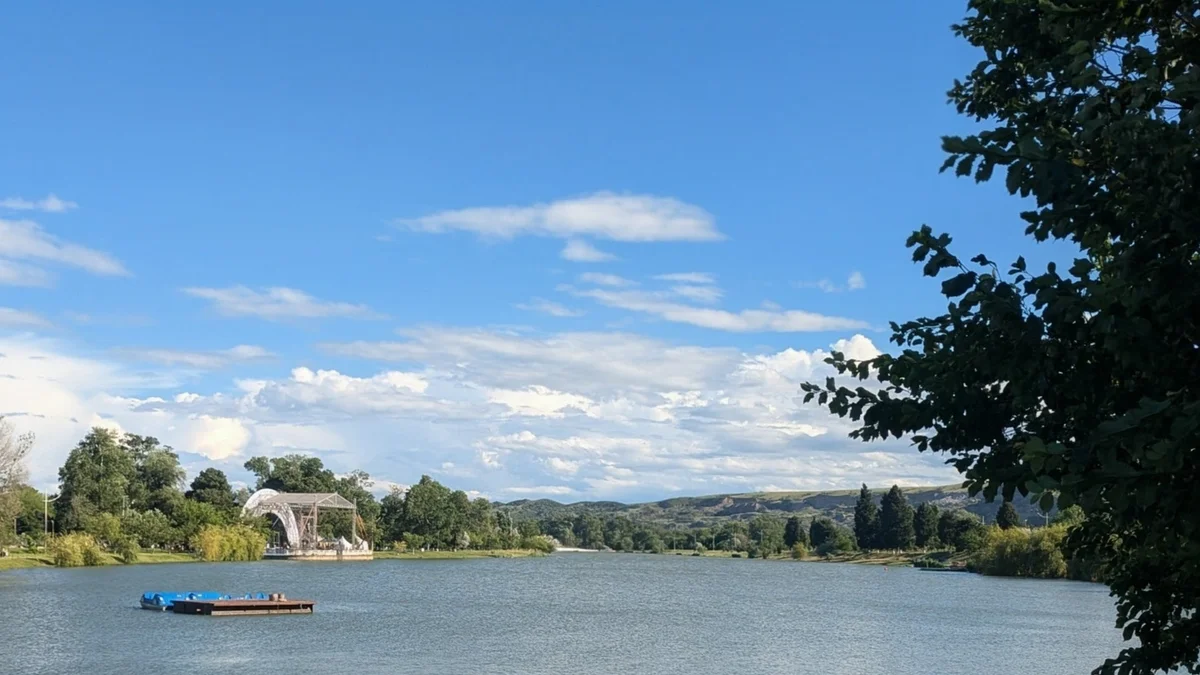The lake in Rustavi Central Park with wooded banks and dry hills beyond, Kvemo Kartli, Georgia
